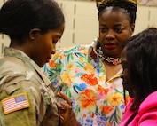 Anastasia Asong pins second lieutenant rank on her niece, Juliana Nkafu, as Euchinie Amindeh looks on.