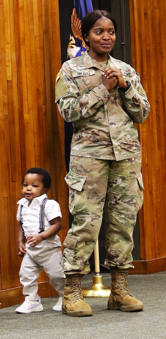 2nd Lt. Juliana Nkafu speaks to a group of officer candidates as her nephew, 13-month-old James Akemanji Nkengayi, also takes the stage at her commissioning ceremony.