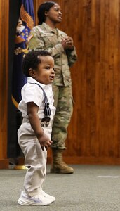2nd Lt. Juliana Nkafu speaks to a group of officer candidates as her nephew, 13-month-old James Akemanji Nkengayi, also takes the stage at her commissioning ceremony.