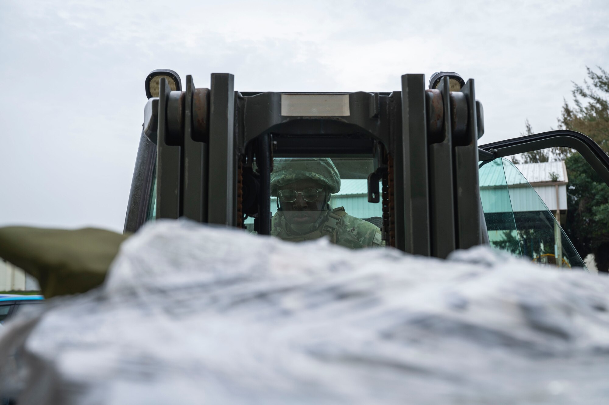 Air Force Member inside of a forklift transports pallets of cots