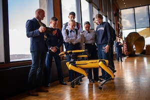 U.S. Coast Guard Academy (USCGA) cadets observe Boston Dynamic’s robot, Spot, controlled by a Massachusetts Institute of Technology (MIT) Lincoln Laboratory researcher (left) at USCGA, New London, Connecticut, Nov. 27, 2023. MIT’s Lincoln Laboratory showcased Spot and its functions to cadets, faculty, and staff.
