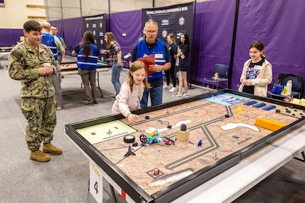 Capt. JD Crinklaw, commander, Puget Sound Naval Shipyard & Intermediate Maintenance Facility, and volunteer Tom Terry observe as two students from Cotton Wood Elementary School compete in the 3rd Annual Navy Peninsula Robotics Competition at North Kitsap High School in Poulsbo, Washington, April 29, 2025. (U.S. Navy photo by Jeb Fach)