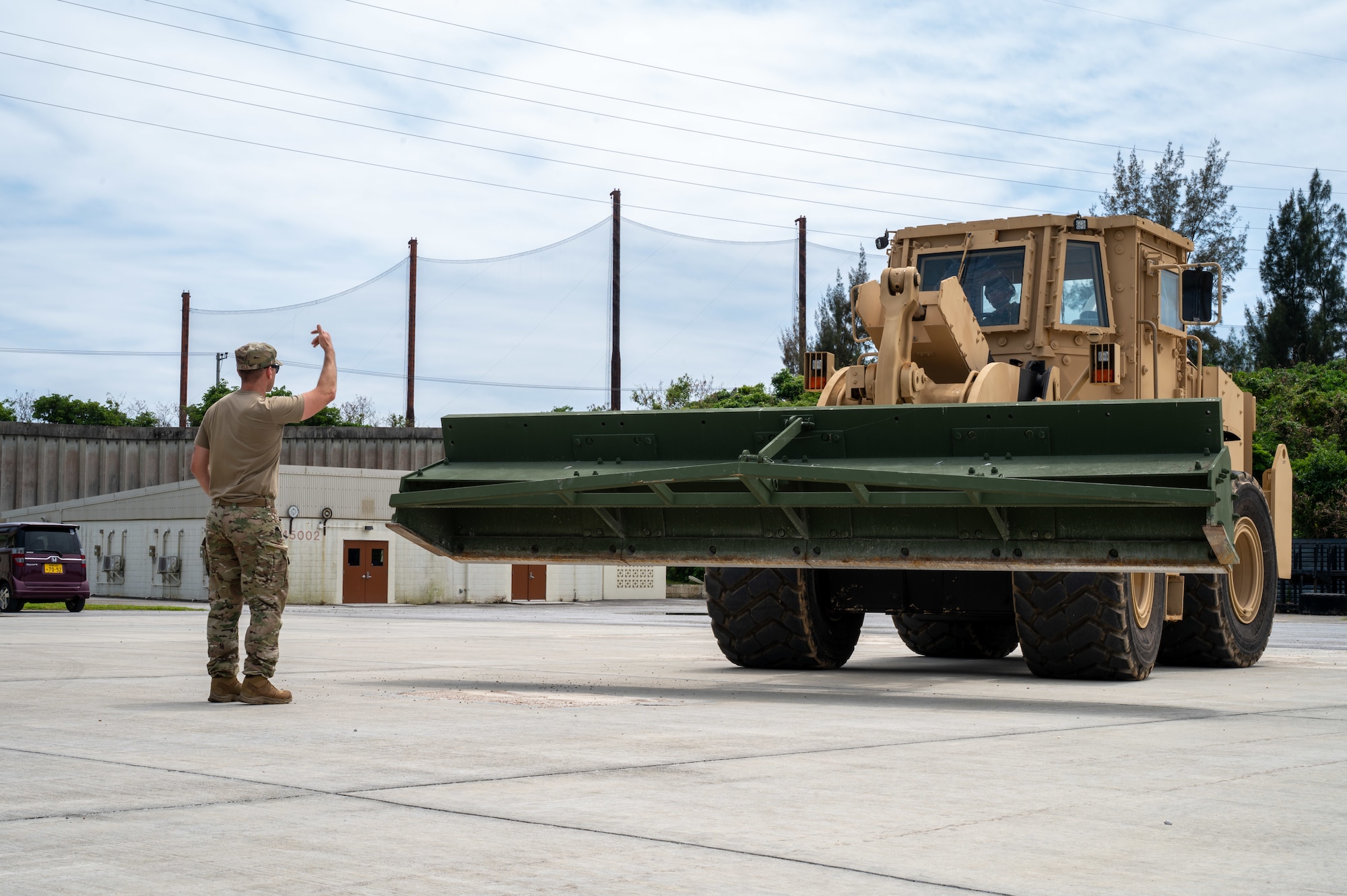 Military members marshals a front loader on a simulated flightline