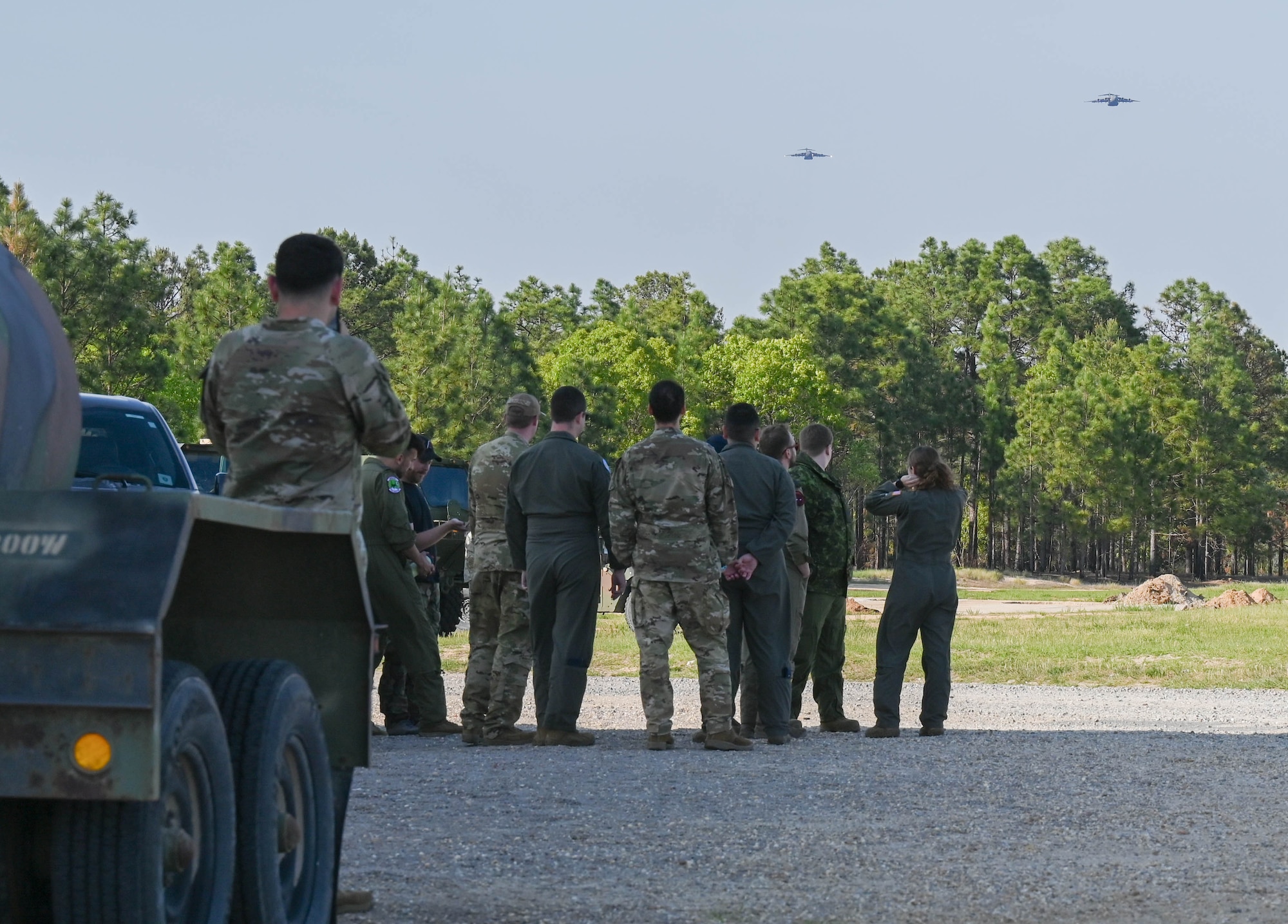 A group of Airmen watch aircraft fly.