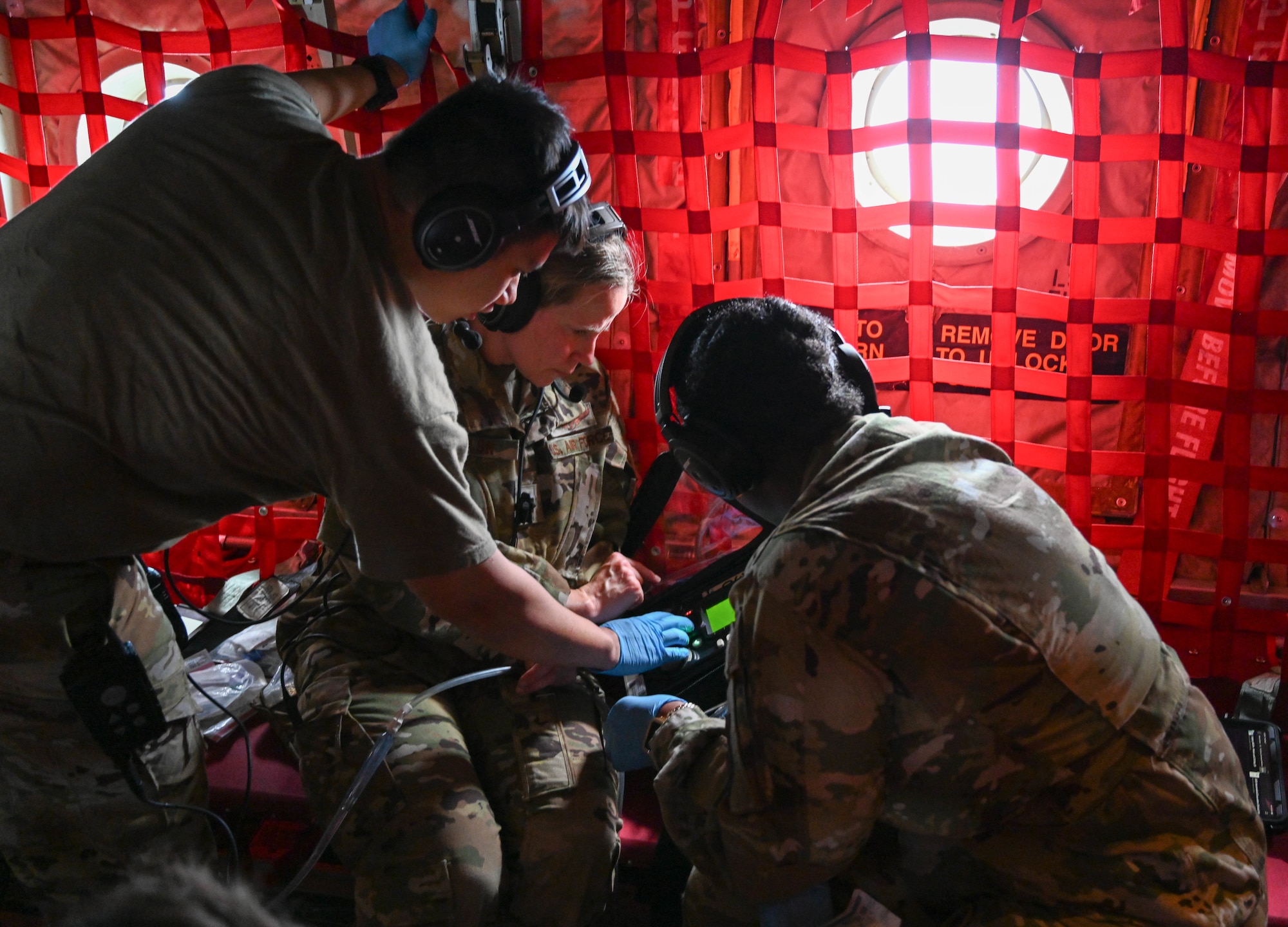 Three Airmen huddle over medical equipment.