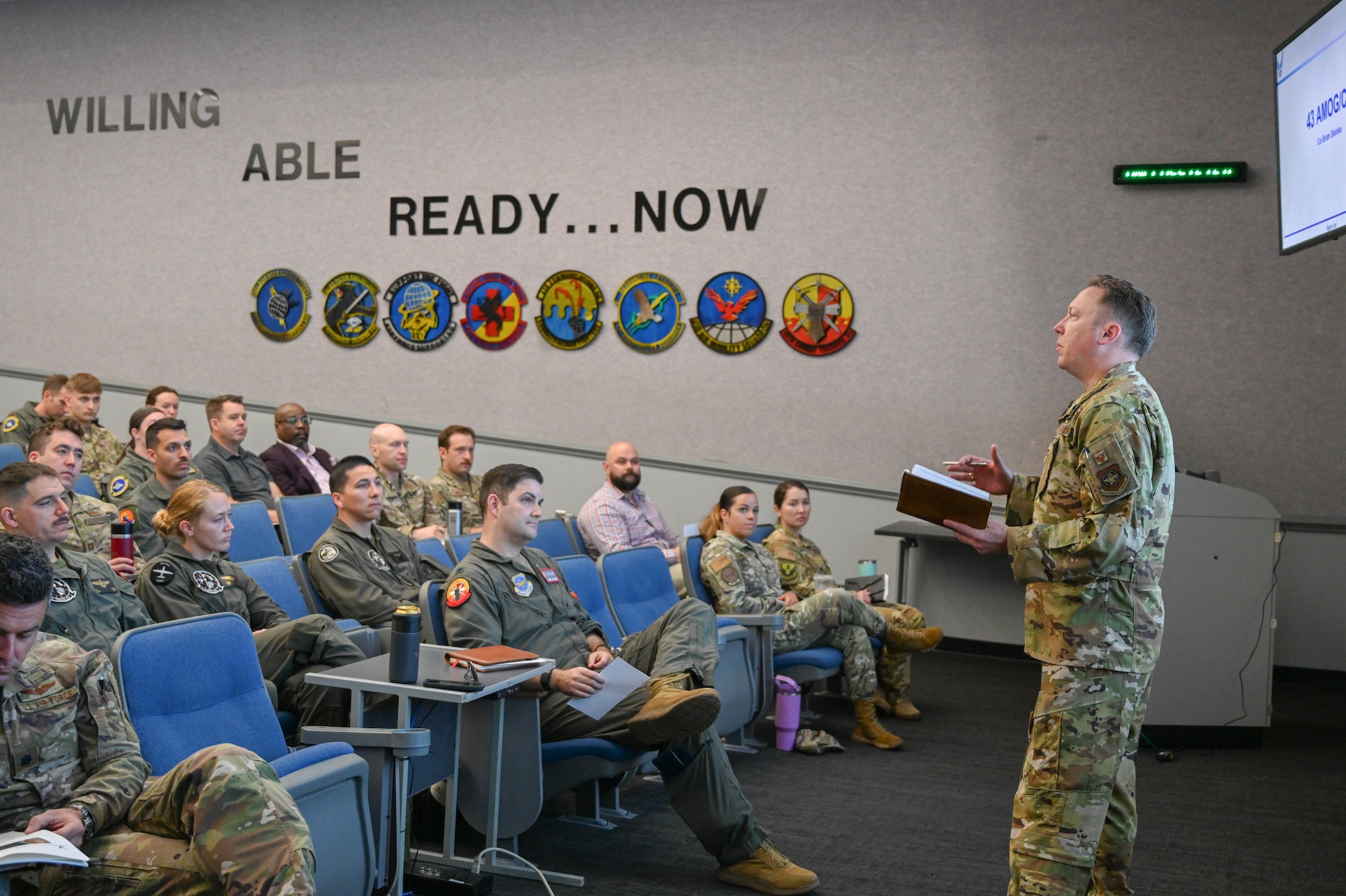 An Airman speaks to a crowd of people.