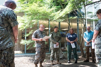 Navy Chaplain Commander Philip Park, second from left, reads a scripture passage during a Blessing of the Hands ceremony held at Naval Health Clinic Cherry Point on Wednesday, May 7.  The spiritual fitness event honored the compassion and professionalism of the nursing staff serving in the facility while fortifying their spiritual resolve.