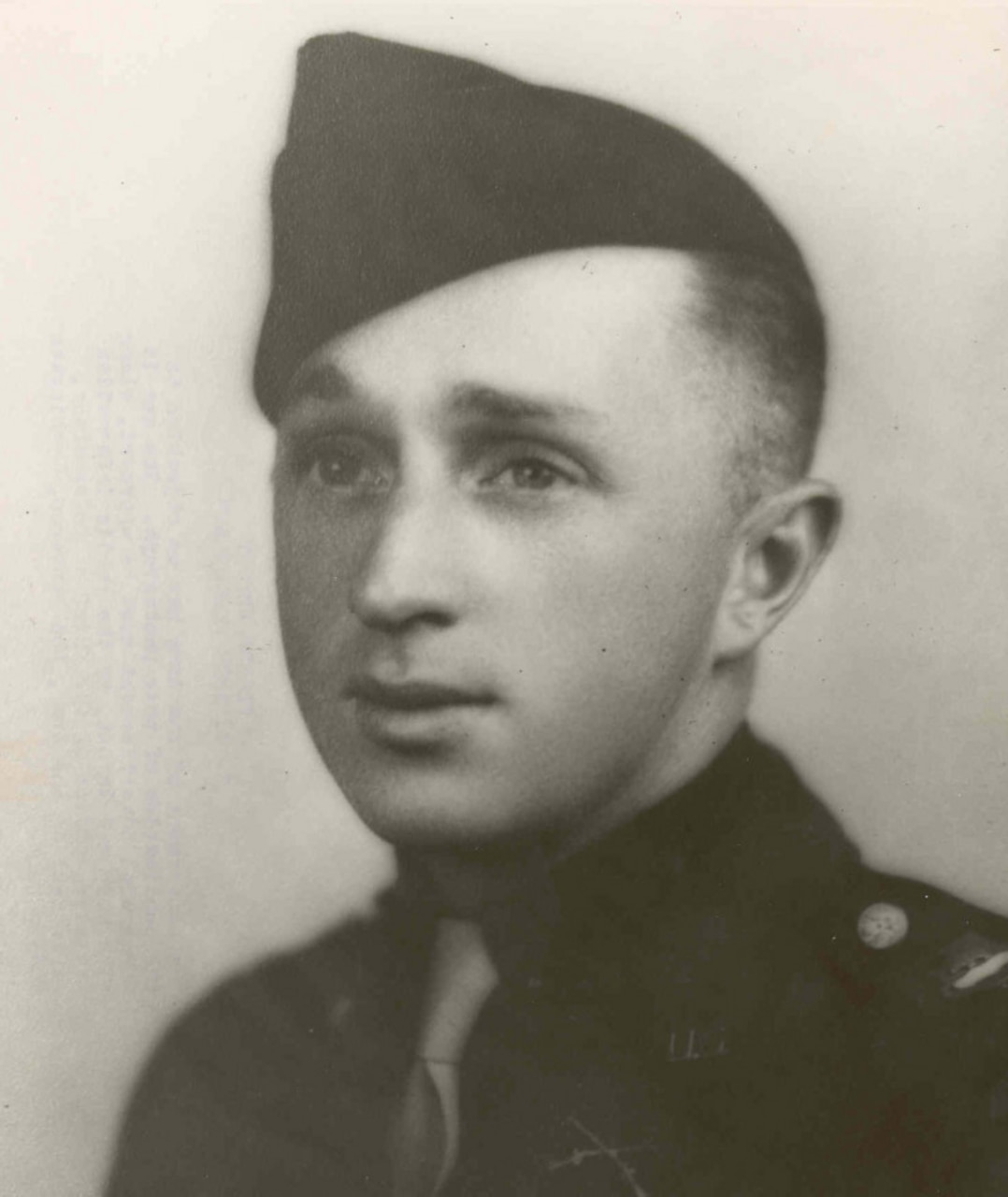 A man in a cap and military uniform poses for a photo.
