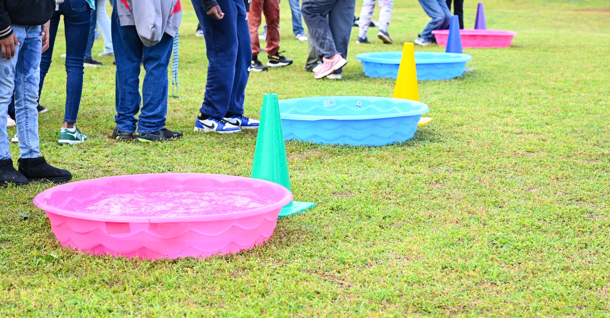 Four colorful kiddie pools are lined in a row as students line up behind them for a game.