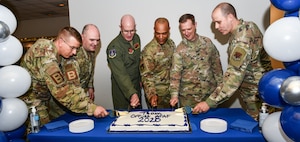 Chief Master Sgt. Michael Moore, 95th Wing command chief, Col. Walter Goss, 95th Wing deputy commander,  Col. Mark Howard, 55th Wing commander, Chief Master Sgt. Andrew Small, 55th Wing command chief, Col. Matthew Sattler, 557th Weather Wing deputy commander, and Chief Master Sgt. Daniel Perry, 557th Weather Wing command chief, cut a cake during the kickoff of Offutt Air Force Base's 2025 Air Force Assistance Fund campaign, May 2. (U.S. Air Force photo by Chad Watkins)