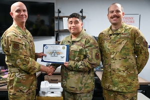 U.S. Air Force Col. Jeff Marshall, 97th Air Mobility Wing (AMW) commander, left, and Chief Master Sgt. Justin Brundage, 97th AMW command chief, right, awards Airman 1st Class Axel Moreno, 97th Communications Squadron (CS) client systems technician, at Altus Air Force Base, Oklahoma, April 24, 2025. The 97th CS develops and implements information technology solutions, provides knowledge management, information assurance, and communications security functions. (U.S. Air Force photo by Airman 1st Class Nathan Langston)