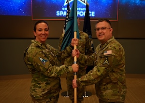 U.S. Space Force Lt. Col. Stephanie Mitchell, Space Delta 1 director of staff, left, passes the Space Delta 1 guidon to U.S. Space Force Chief Master Sgt. Ryan Dawson.
