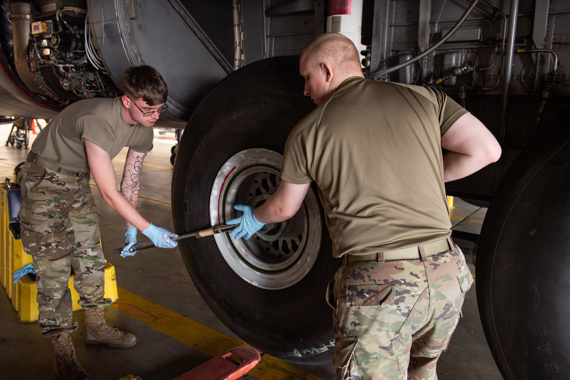 Two Airman work together to install a tire back on a C-130J Super Hercules.