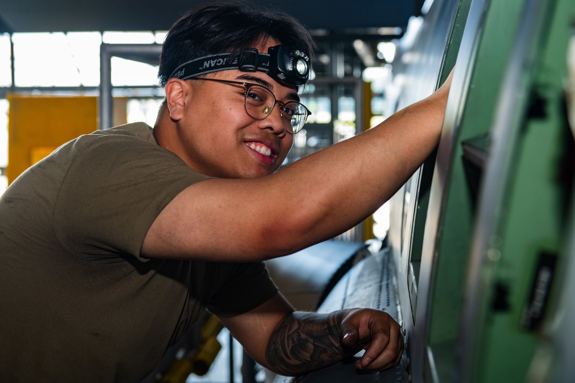 An Airman smiles for the camera as they are performing maintenance on a C-130J Super Hercules.