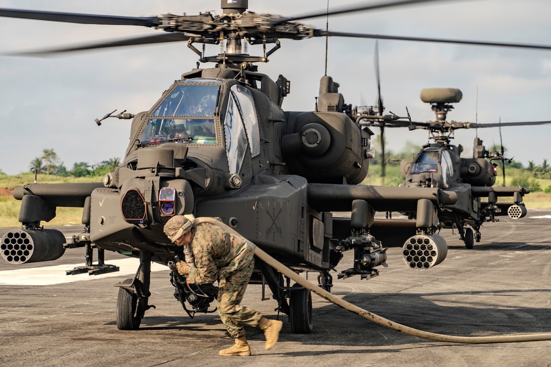 A U.S. Marine with Marine Wing Support Squadron 174, Marine Aircraft Group 24, 1st Marine Aircraft Wing, runs with a refueling hose to refuel an AH-64 Apache assigned to 2nd Squadron, 6th Cavalry Regiment, 25th Combat Aviation Brigade, 25th Infantry Division, in support of Exercise Balikatan 25, April 29, 2025.