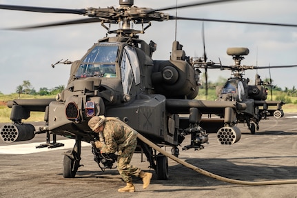 A U.S. Marine with Marine Wing Support Squadron 174, Marine Aircraft Group 24, 1st Marine Aircraft Wing, runs with a refueling hose to refuel an AH-64 Apache assigned to 2nd Squadron, 6th Cavalry Regiment, 25th Combat Aviation Brigade, 25th Infantry Division, in support of Exercise Balikatan 25, April 29, 2025.
