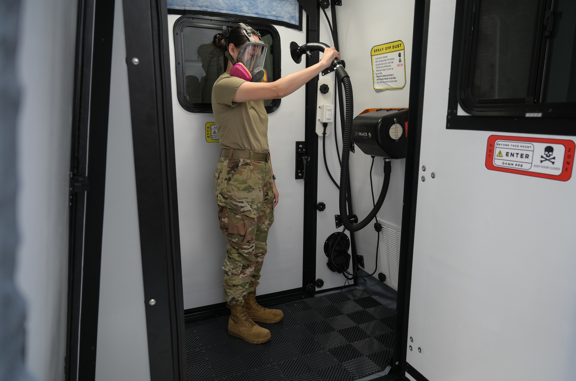 Airman in a protective masking using an air shower.