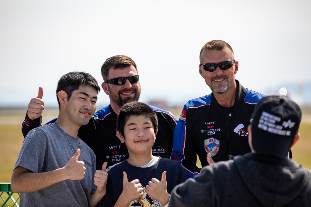 Matt Harvey, center, the Director of Operations for Team Fastrax, and Larry Compton, right, an Exhibition Skydiver at Team Fastrax, both natives of Ohio, pose for a photo with guests during Family Day at Marine Corps Air Station Iwakuni, Japan, May 3, 2025. Family Day allowed both U.S. and Japanese members of the MCAS Iwakuni community, their family members, local orphanages, and members of the local community with special needs the ability to experience a small-scale Friendship Day during the air show rehearsal that showcased the strength of the U.S.-Japan Alliance. (U.S. Marine Corps photo by Sgt. Isaac Orozco)