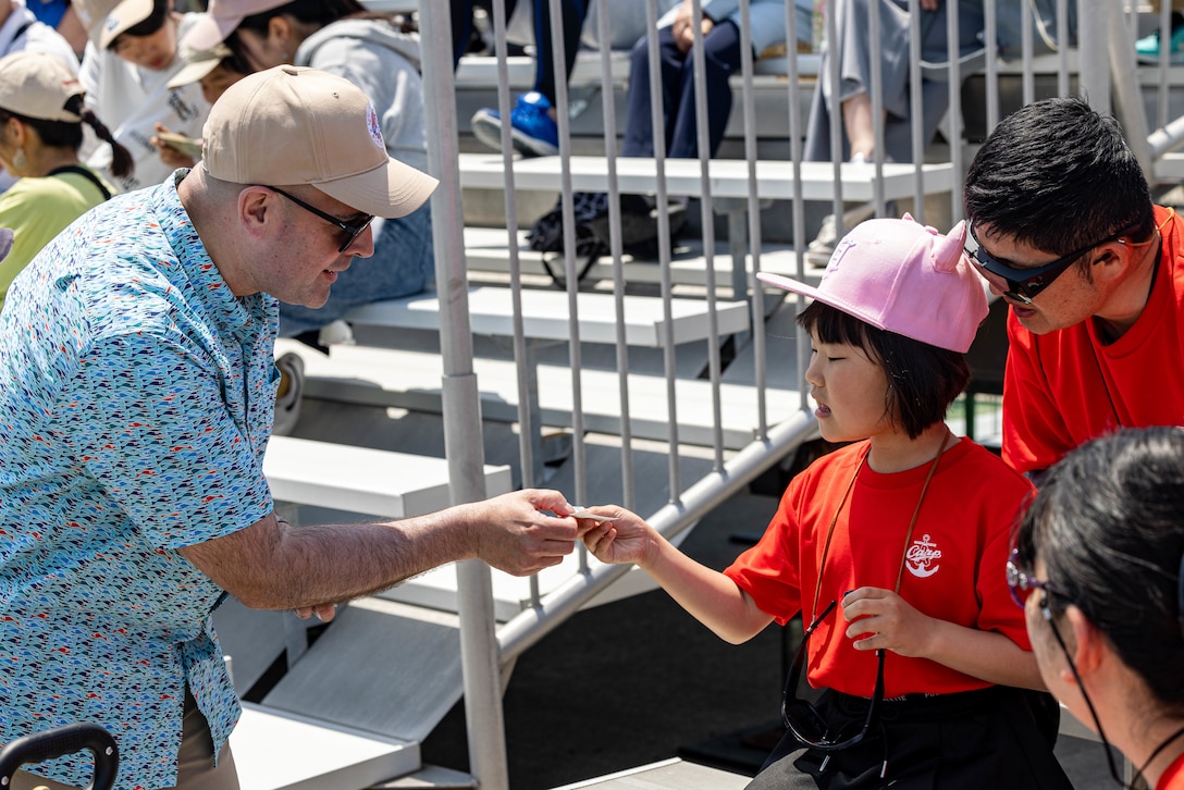 U.S. Marine Corps Col. Richard Rusnok, left, the commanding officer of Marine Corps Air Station Iwakuni, and a native of Pennsylvania, gives a child a sticker during Family Day at MCAS Iwakuni, Japan, May 3, 2025. Family Day allowed both U.S. and Japanese members of the MCAS Iwakuni community, their family members, local orphanages, and members of the local community with special needs the ability to experience a small-scale Friendship Day during the air show rehearsal, which showcased the strength of the U.S.-Japan Alliance.​ (U.S. Marine Corps photo by Cpl. Dahkareo Pritchett)