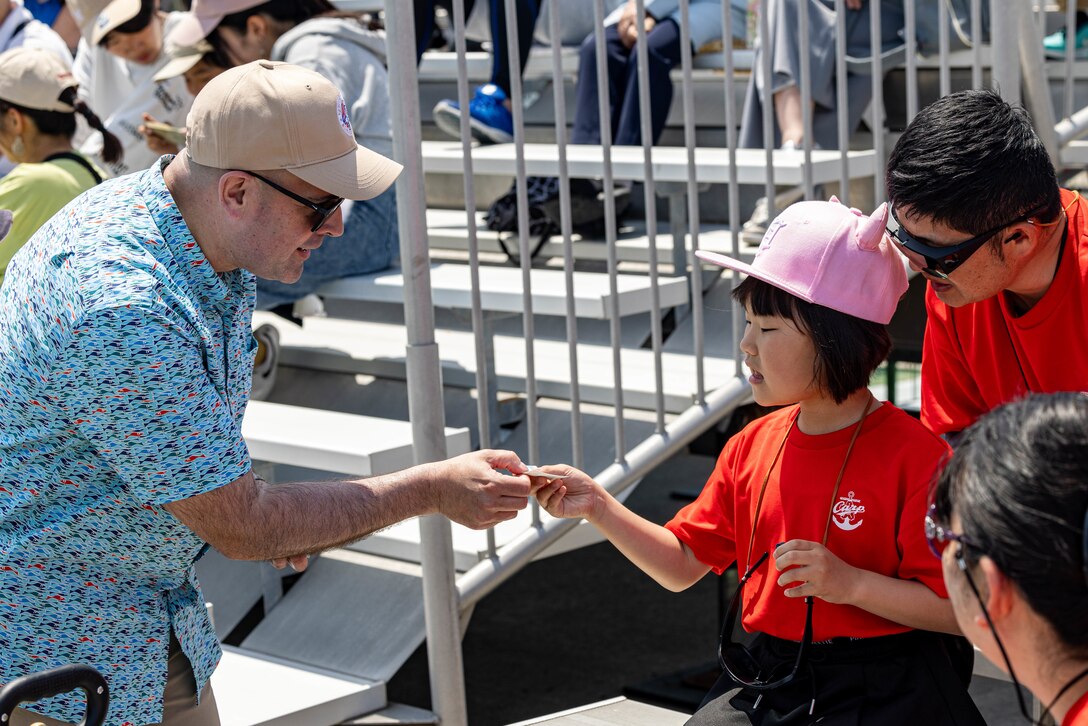 U.S. Marine Corps Col. Richard Rusnok, left, the commanding officer of Marine Corps Air Station Iwakuni, and a native of Pennsylvania, gives a child a sticker during Family Day at MCAS Iwakuni, Japan, May 3, 2025. Family Day allowed both U.S. and Japanese members of the MCAS Iwakuni community, their family members, local orphanages, and members of the local community with special needs the ability to experience a small-scale Friendship Day during the air show rehearsal, which showcased the strength of the U.S.-Japan Alliance.​ (U.S. Marine Corps photo by Cpl. Dahkareo Pritchett)