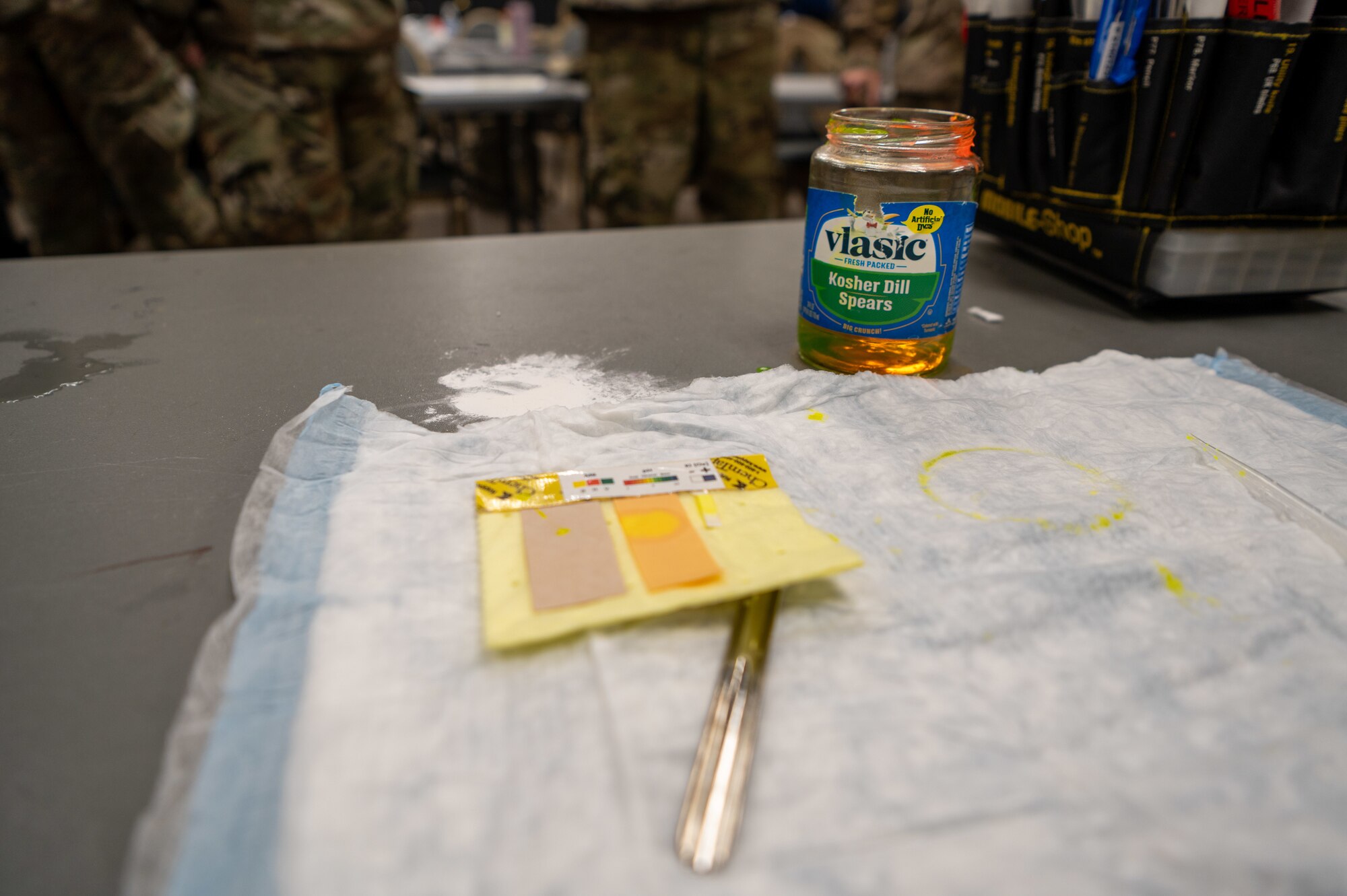 Fake hazardous material is used during classroom instruction to demonstrate using detection strips during a hands-on CBRN response exercise at Goldwater Air National Guard Base, Ariz, Jan. 31, 2025. This training enhances rapid decision-making and operational readiness in emergency situations. (U.S. Air Force photo by Staff Sgt. Alexis Orozco)