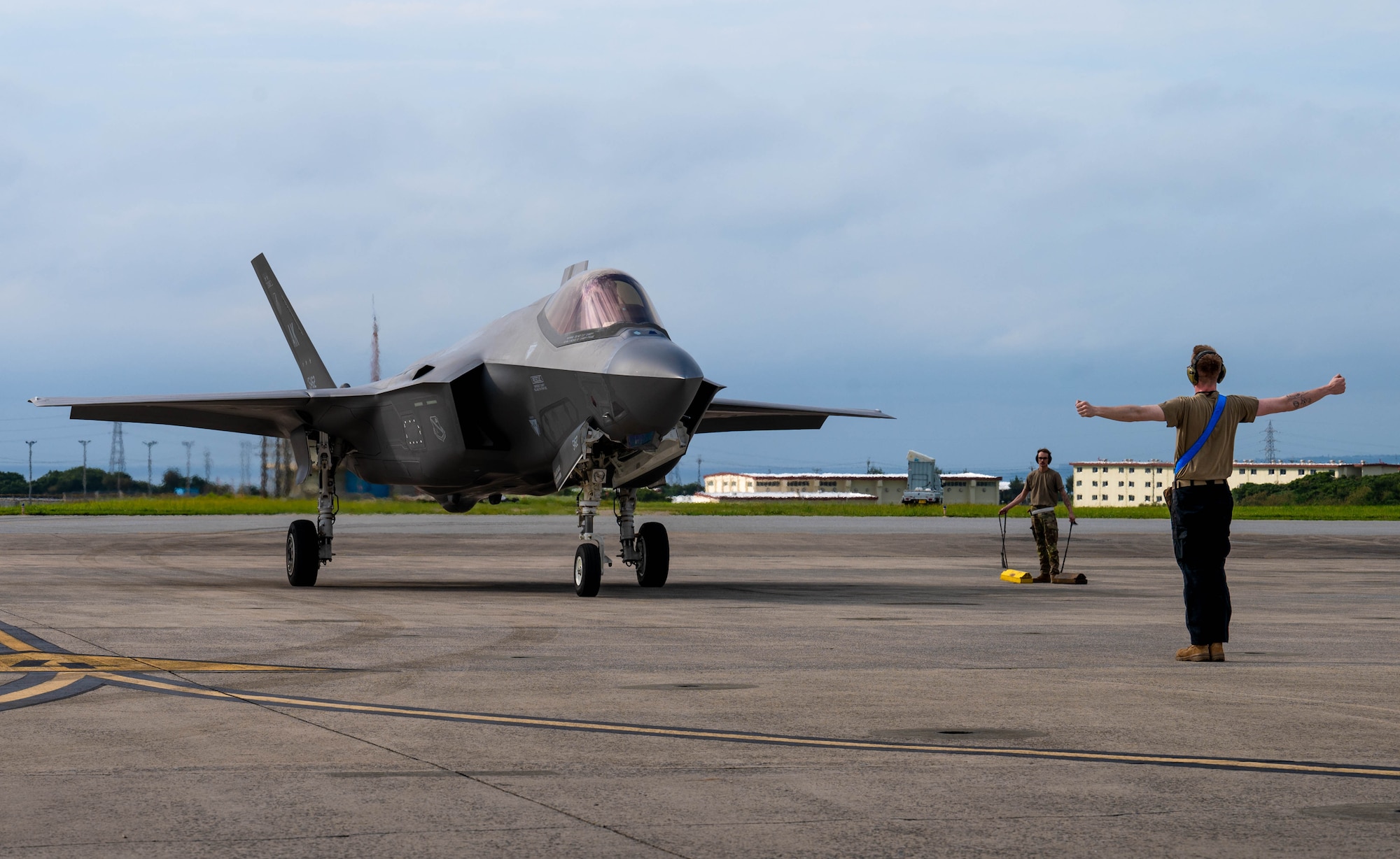 A U.S. Air Force crew chief assigned to the 355th Expeditionary Fighter Generation Squadron marshals an F-35A Lightning II into a parking spot at Marine Corps Air Station Futenma, Japan during a routine 18th Wing readiness exercise at Kadena Air Base, Japan, May 6, 2025.