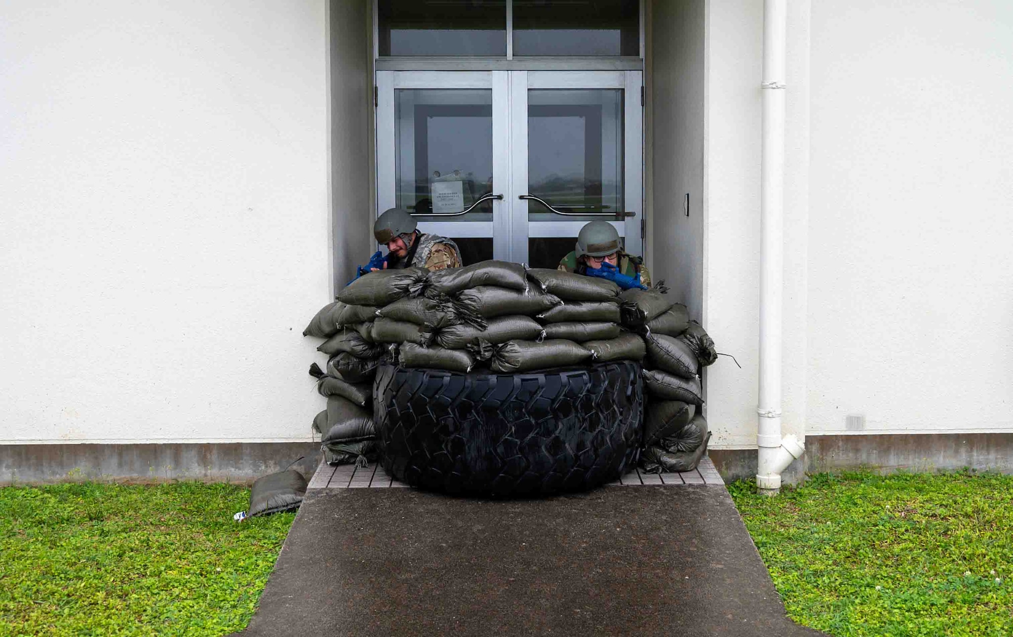 Two service members on a pile of sand bags participating in the exercise.