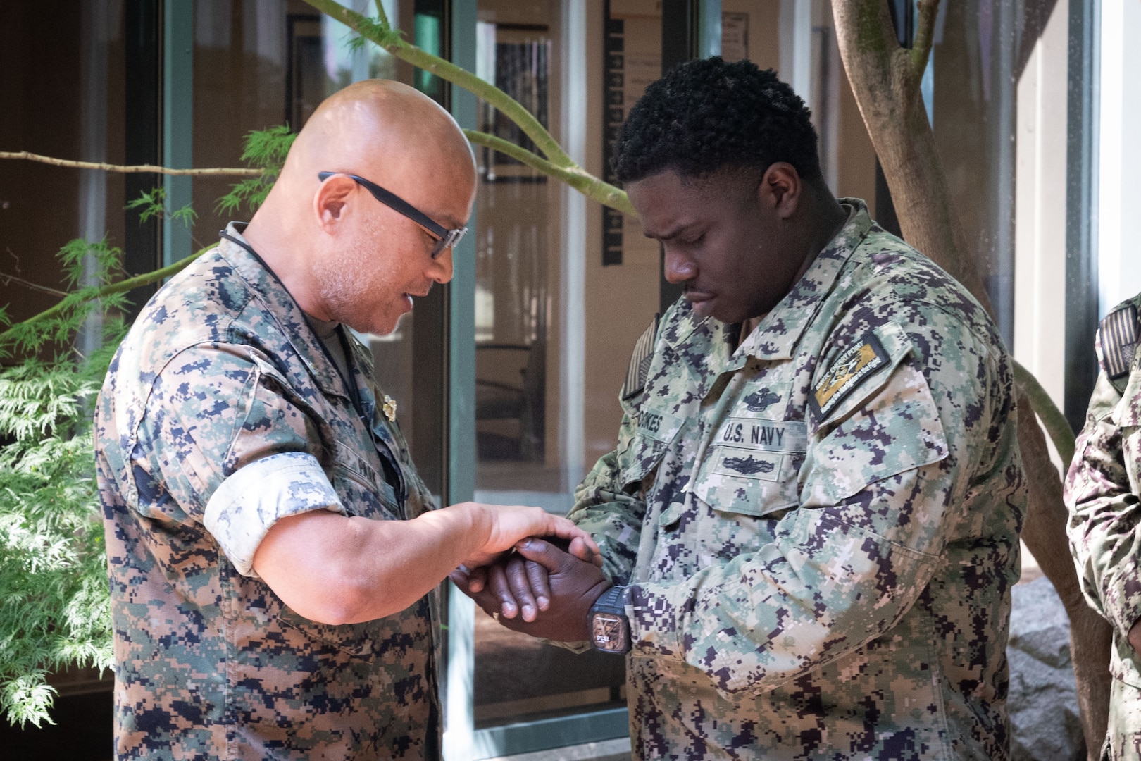 Lieutenant Commander William Hookes, right, a Nurse serving aboard Naval Health Clinic Cherry Point, prays with Navy Chaplain Commander Philip Park during a Blessing of the Hands ceremony Wednesday, May 7.  The spiritual fitness event honored the compassion and professionalism of the nursing staff serving in the facility while fortifying their spiritual resolve.