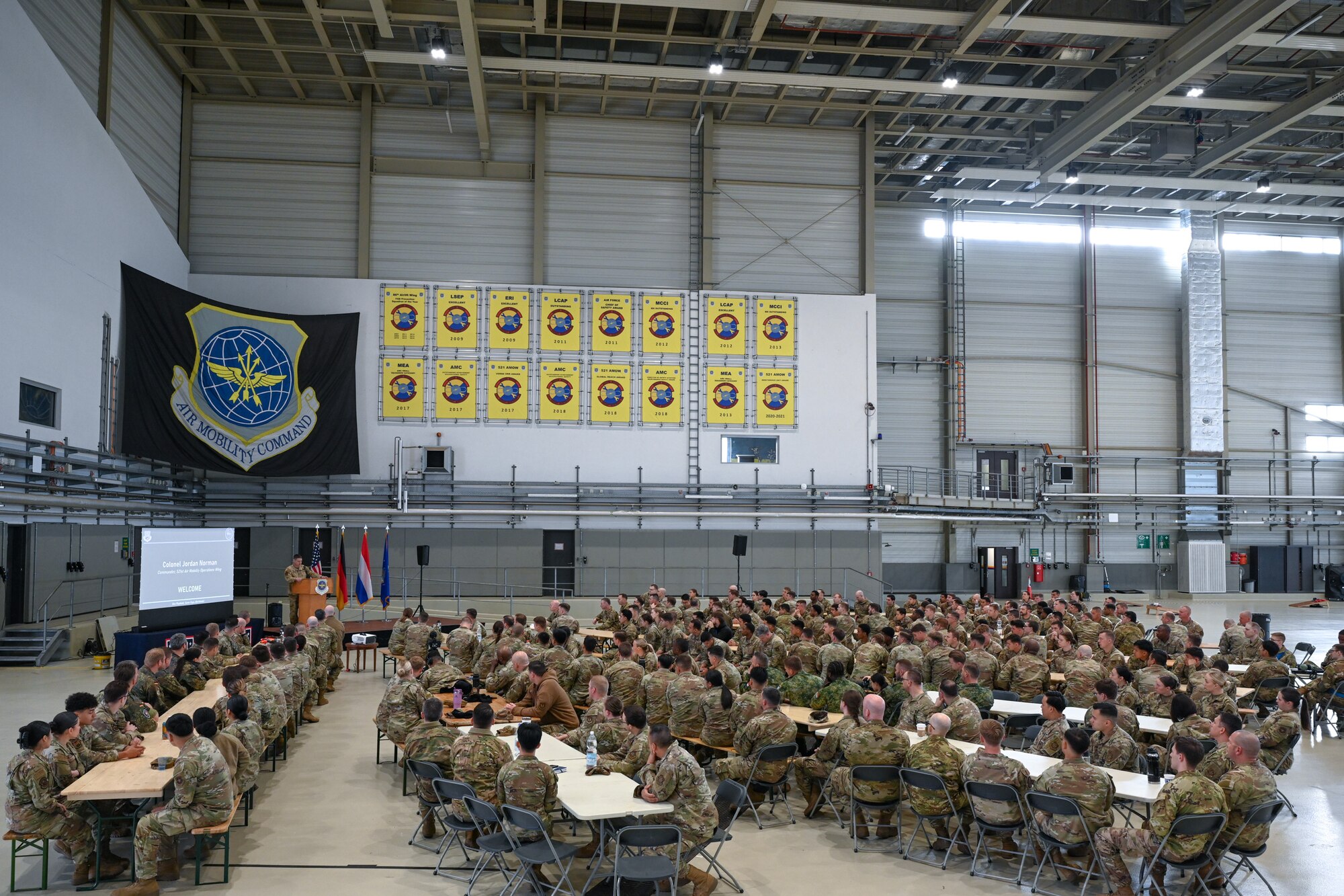 U.S. Air Force Col. Jordan Norman, on stage, 521st Air Mobility Operations Wing commander, gives opening remarks to members participating in the 521st AMOW’s Mobility Vanguard 2025, in Hangar 5 at Ramstein Air Base, Germany, April 23, 2025.