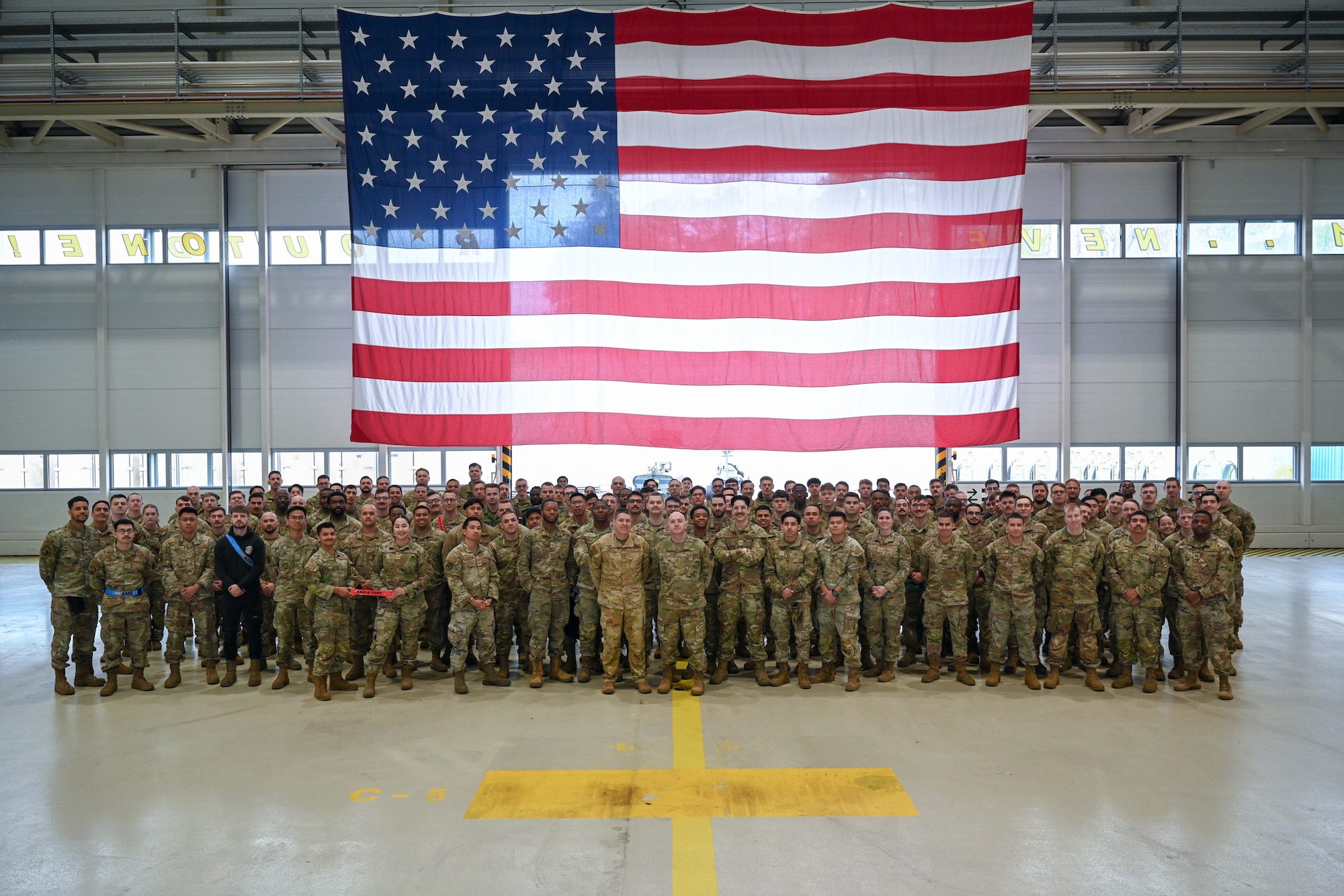 U.S. Air Force Col. Jordan Norman, center left, 521st Air Mobility Operations Wing commander, and Chief Master Sgt. Scott Piper, center right, 521st AMOW command chief, pose for a group photo with participating members in the 521st AMOW’s Mobility Vanguard 2025, in Hangar 5 at Ramstein Air Base, Germany, April 23, 2025.
