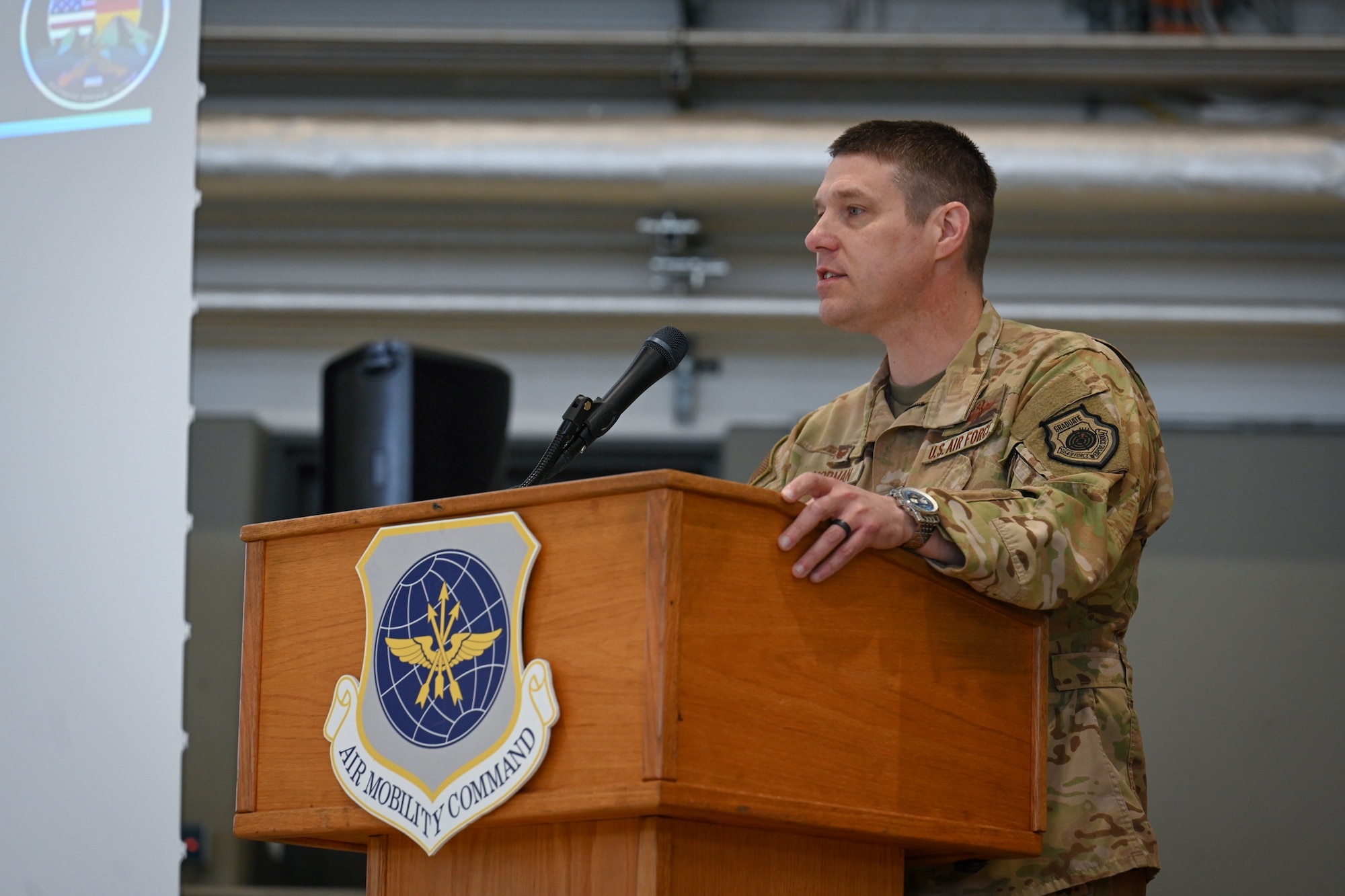 U.S. Air Force Col. Jordan Norman, on stage, 521st Air Mobility Operations Wing, gives opening remarks to members participating in the 521st AMOW’s Mobility Vanguard 2025, in Hangar 5 at Ramstein Air Base, Germany, April 23, 2025.