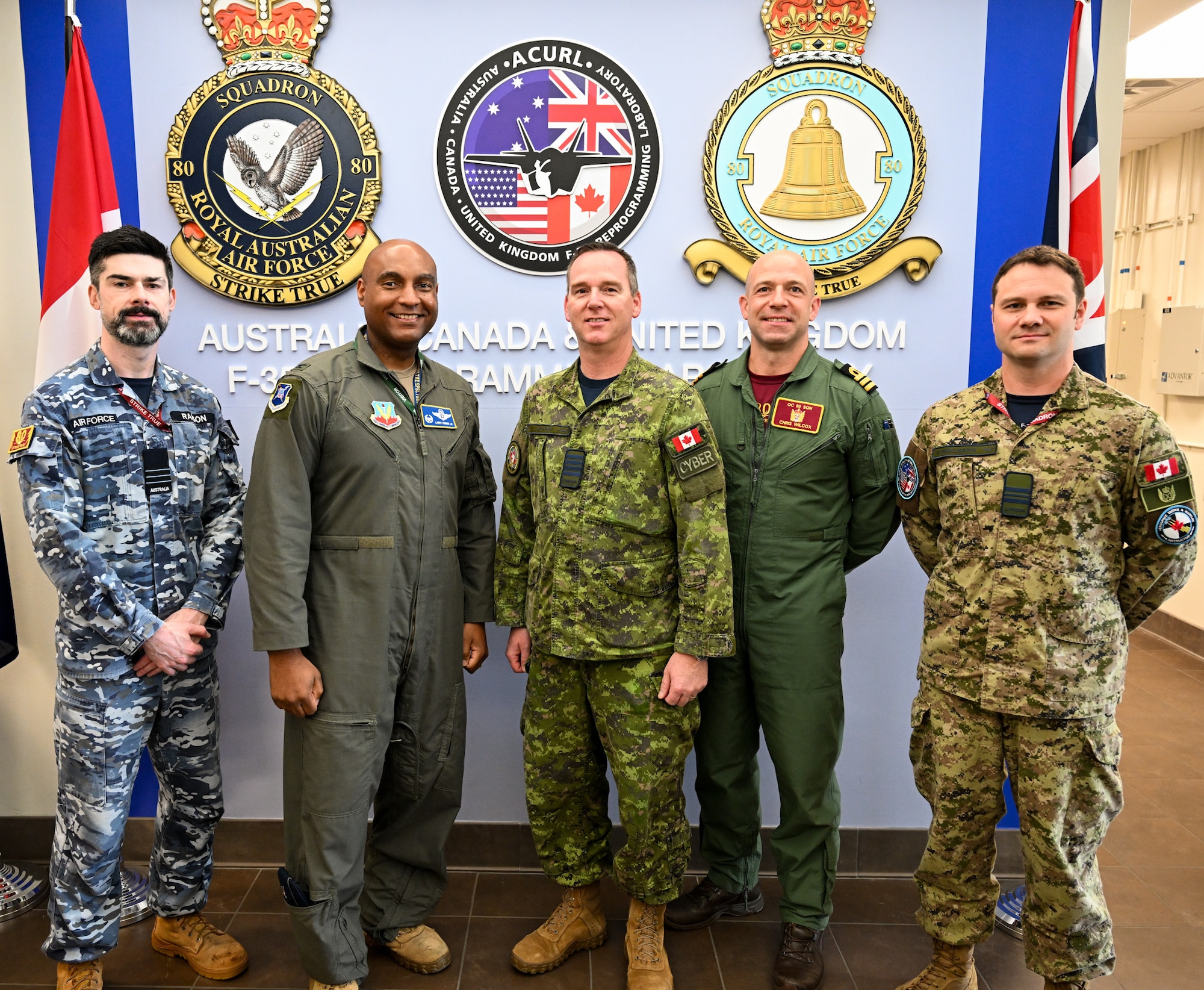 U.S. Air Force Col. Larry Fenner Jr., 350th Spectrum Warfare Wing commander, second from left, stands next to Canadian Armed Forces Col. John Roper, Canadian Armed Forces Cyber Command director SIGINT, center, during a visit to the No. 80 Squadron at Eglin Air Force Base, Florida, April 24, 2025. The visit was to engage with the No. 80 Squadron, who supports F-35 mission data file reprogramming efforts for the three nations and is home to service members from each military and it provided an opportunity for wing leadership to discuss how to further the EMSO enterprise between the U.S. and its partners. (U.S. Air Force photo by SrA Anna Smith)