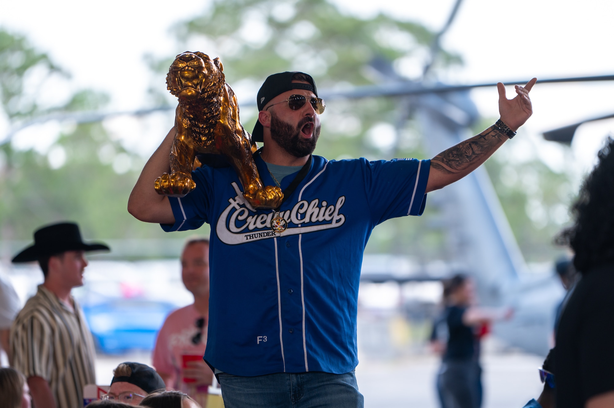 With one arm raised, and another holding a golden tiger statue, a man cheers.
