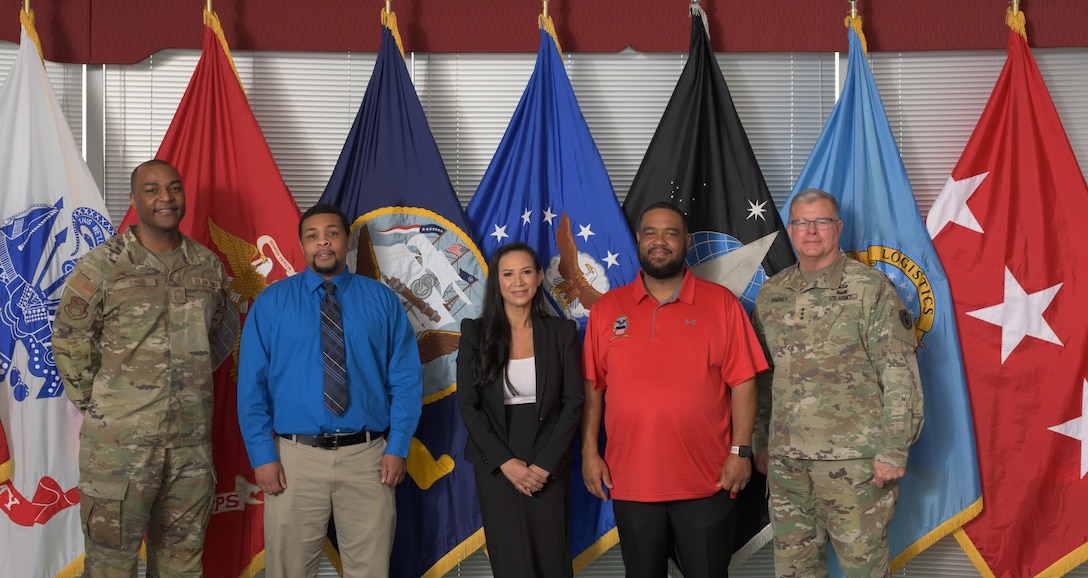 Five people pose for photo after coin presentation.