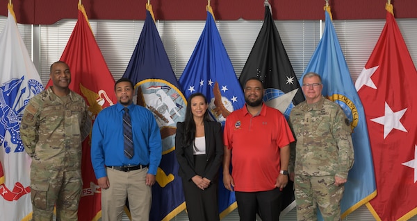 Five people pose for photo after coin presentation.