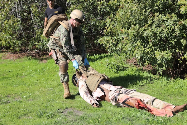Lt. Joshua Grimes, physician assistant with Expeditionary Resuscitative Surgical System (ERSS) 7   , drags a simulated casualty to safety during a tactical combat casualty care (TCCC) familiarization scenario as part of the ERSS course at Naval Expeditionary Medicine Warfighter Development Center Apr. 14. The scenario incorporates realistic moulage, role players, and battlefield effects to enhance trauma response and prepare the team for operational deployment in austere environments. Grimes talks about the battle effects and says, “It really heightened up the desire and the need to really pay attention and focus on the patients. I have never experienced anything like that at any other simulations, so I thought it was phenomenal especially when you felt the “boom” in your chest.” (U.S. Navy photo by Petty Officer 2nd Class Kwame Obengyeboah)