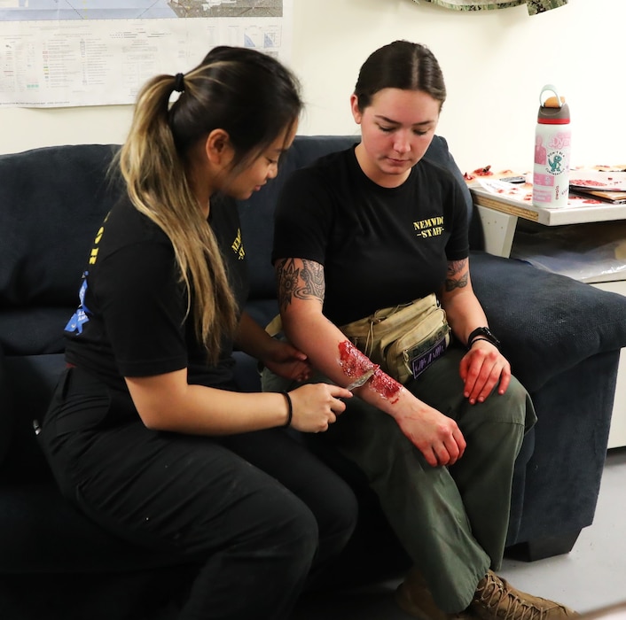 Hospital Corpsman 2nd Class Moira Esquivel (left) applies a burn moulage on Hospital Corpsman 3rd Class Abbigail Dunlap (right), moulage technician with Naval Expeditionary Medicine Warfighter Development Center (NEMWDC), using silicon to simulate blast injuries during an Expeditionary Resuscitative Surgical System course at NEMWDC, Apr. 14. The realistic wounds help immerse students in combat medical simulations and reinforce rapid trauma assessment skills. (U.S. Navy photo by Petty Officer 1st Class Trevin Perry)