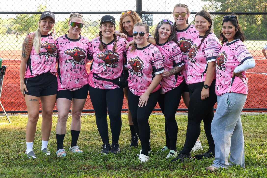 A group of people in matching pink t-shirts smile for a photo on a field.