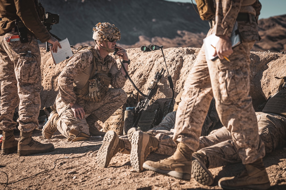 U.S. Marine Corps 1st Lt. John Collier, a Ramona, California native, field artillery officer with 5th Battalion, 14th Marine Regiment, 4th Marine Division, talks on the radio during a Fire Support Coordination Exercise as part of Service Level Training Exercise 0-25 at Training Area Quackenbush, Marine Corps Air-Ground Combat Center, Twentynine Palms, California, Dec. 6, 2024. FSCEX is a live-fire training event integrating infantry battalion combat operations center functions, distributed artillery, mobile fire support teams, close air support assets, and electronic warfare support teams. SLTE 0-25 is designed to enhance readiness across core Mission Essential Tasks and prepare Marines for Force-on-Force operations.  (U.S. Marine Corps photo by Lance Cpl. Enge You)