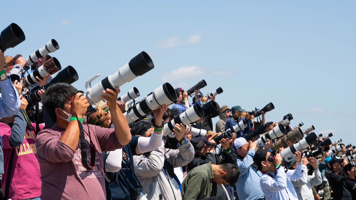 large group of photographers point their lenses toward the sky