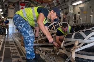 Royal Australian Airman pushes cargo.
