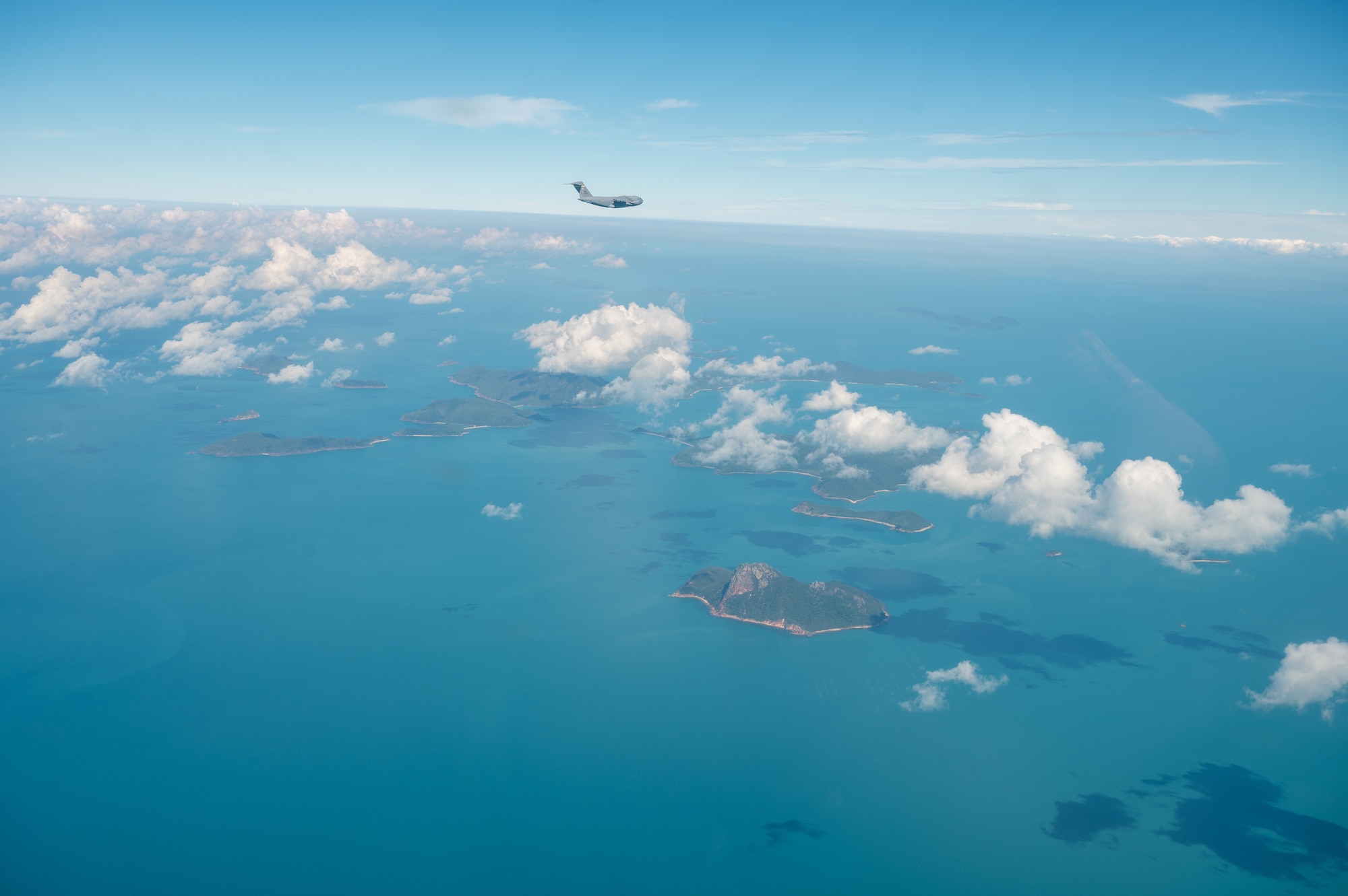 A U.S. Air Force C-17 Globemaster assigned to the 535th Airlift Squadron at Joint Base Pearl Harbor-Hickam flies over an island off the coast of Australia.