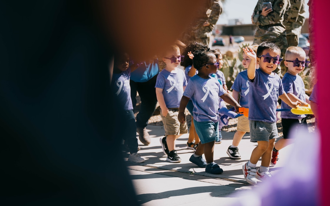 Children from the Luke Air Force Base Child Development Center wave during the Purple Up parade, April 25, 2025, at Luke Air Force Base, Arizona.