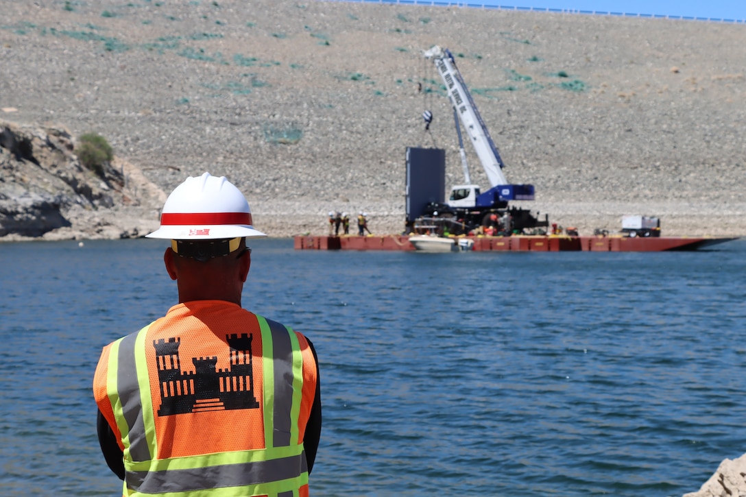 Sam Law, a quality assurance specialist with the Los Angeles District, observes a barge carrying a bulkhead gate April 29 for installation at Alamo Dam near Wendon, Arizona.  The bulkhead gate installation is required before inspection and maintenance can begin on the operated dam by the U.S. Army Corps of Engineers.