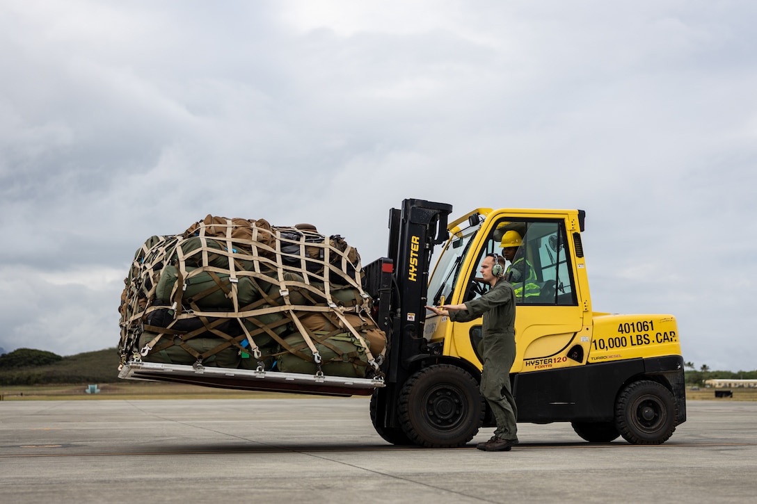 A U.S. Marine with 3d Littoral Logistics Battalion, 3d Marine Littoral Regiment, 3d Marine Division, and a U.S. Marine with Marine Aerial Refueler Transport Squadron 153 (VGMR-153), Marine Aircraft Group 24, 1st Marine Aircraft Wing, walking, transport gear and equipment to a KC-130J Hercules assigned to VGMR-153 on Marine Corps Air Station Kaneohe Bay, Hawaii, Jan. 8, 2025. VMGR-153 supported 3d MLR in their annual pre-deployment training exercise on the Big Island of Hawaii, where Marines and Sailors get realistic training with new equipment, integrate with other sections to complete missions, and improve skills, tactics, techniques and procedures. (U.S. Marine Corps photo by Cpl. Malia Sparks)