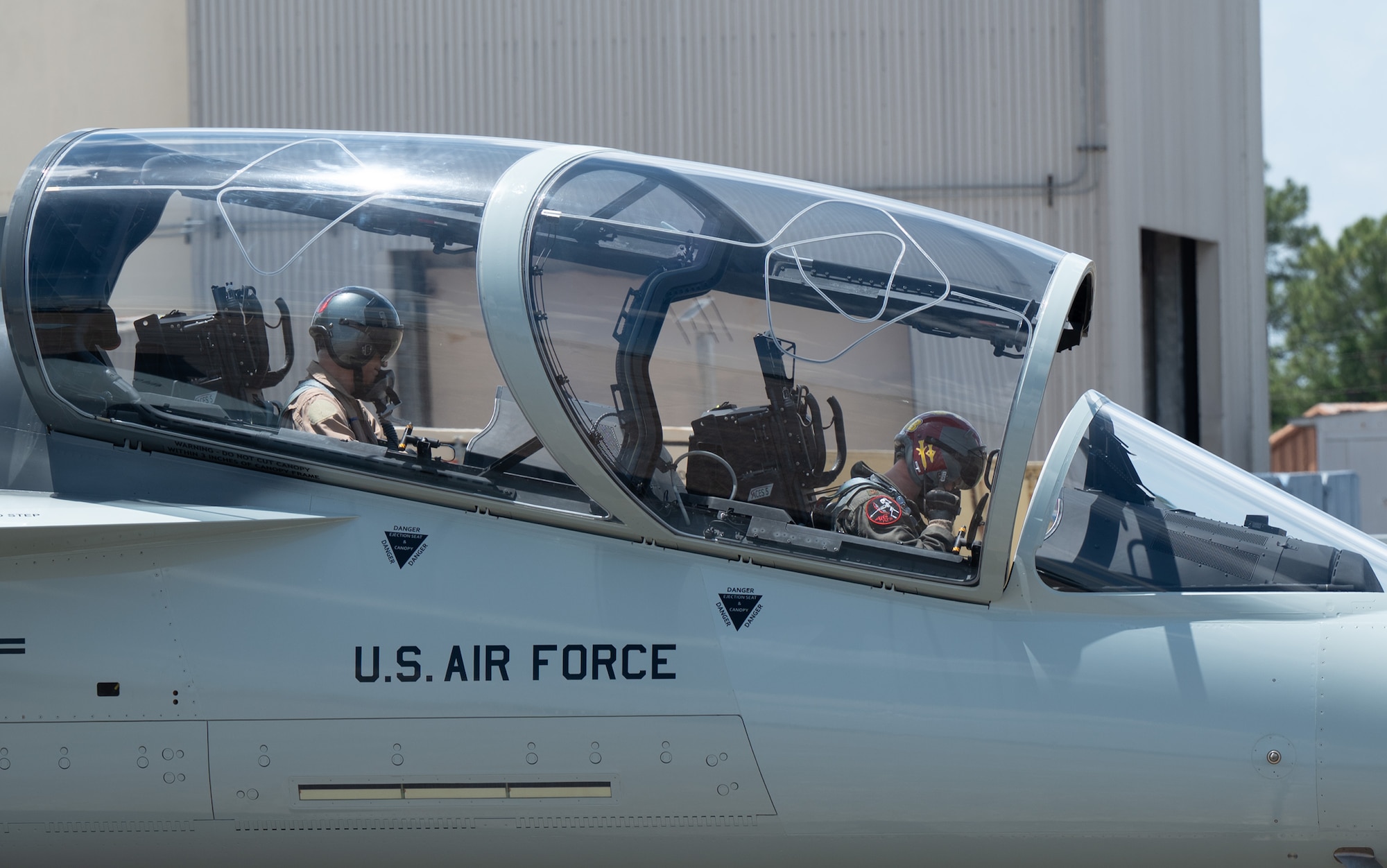 Pilots sit in the cockpit of a T-7A Red Hawk.
