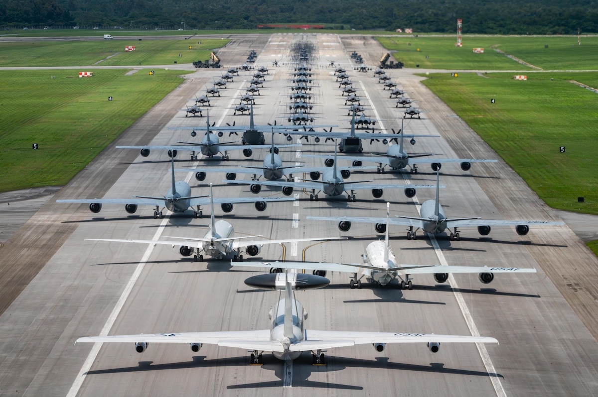 Dozens of aircraft of varying sizes line up on a runway.