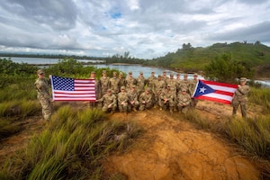 A group of soldiers pose by a river, holding flags.