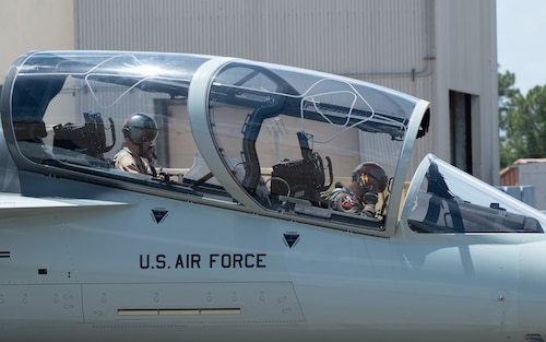 Pilots sit in the cockpit of a T-7A Red Hawk.
