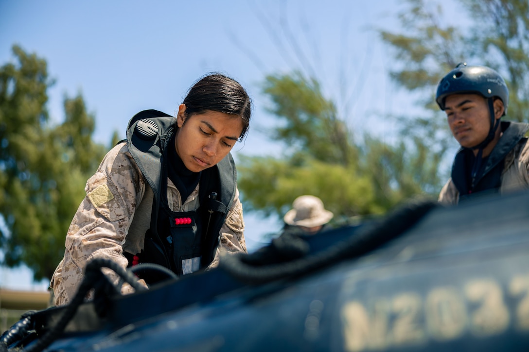 U.S. Marine Corps Lance Cpl. Mariela Mederoa secures supplies in a combat rubber raiding craft during a Maritime Operators (MOP) course at White Beach Naval Facility, April 14, 2025. The MOP course is a six-week, multi-phase course that includes open water safety swimmer, scout swimmer, maritime navigation, combat rubber raiding craft operator, and full mission profile training. MOP is developed by the Expeditionary Operations Training Group and designed to support operations with the Autonomous Low-Profile Vessel capability. Mederoa, a native of California, is a logistics specialist with 12th Littoral Logistics Battalion, 12th Marine Littoral Regiment, 3d Marine Division. (U.S. Marine Corps photo by Lance Cpl. Matthew Morales)